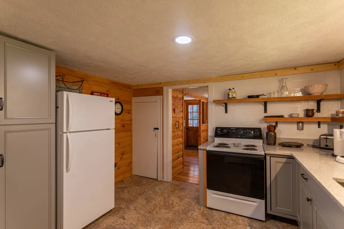 A kitchen scene with stainless steel appliances, open shelving, and warm wooden accents. The space is designed for both cooking and entertaining, with ample room for family or friends to gather and participate in meal preparation.